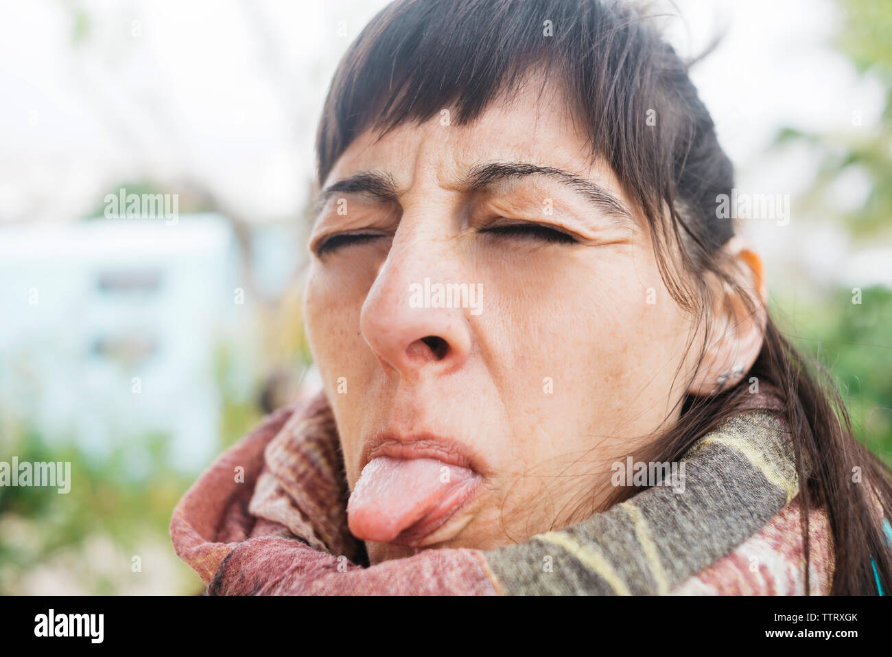 Ritratto di donna gli occhi chiusi mentre spuntavano lingua all'aperto Foto Stock