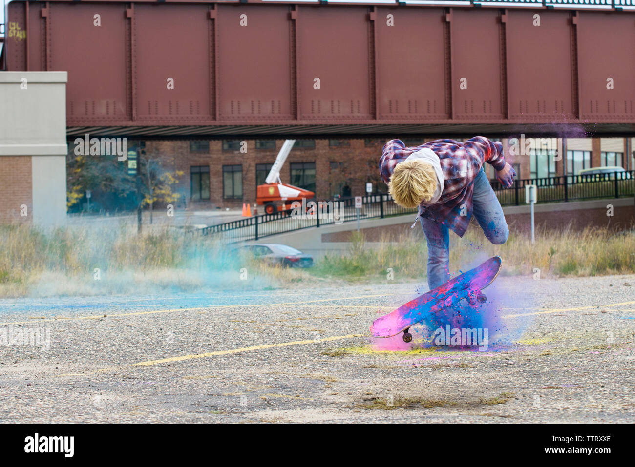 Uomo con vernice a polvere lo skateboard sul sentiero in città Foto Stock