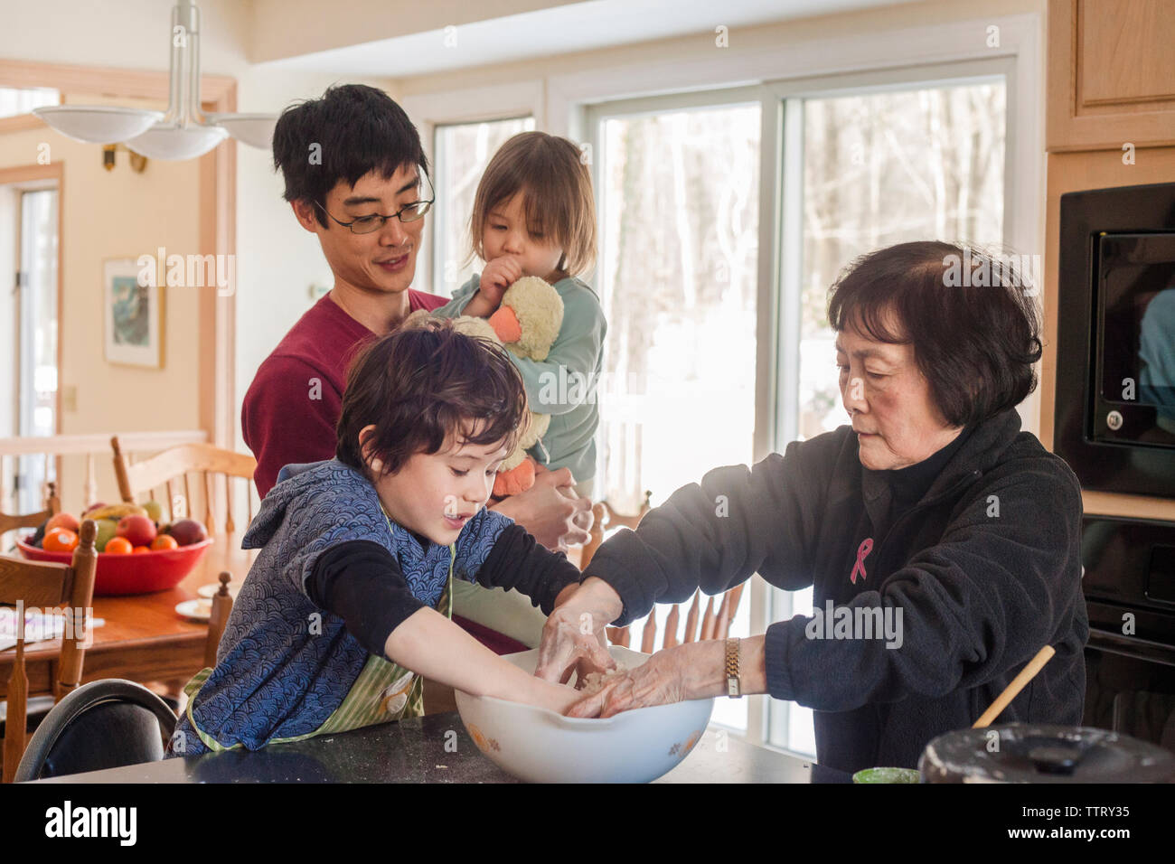 Padre che porta la figlia mentre in piedi dalla famiglia la preparazione di cibi a casa Foto Stock