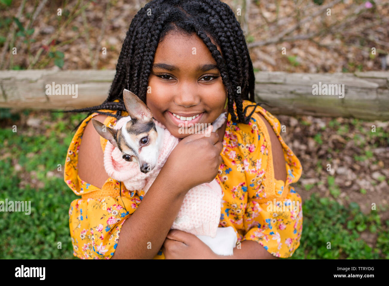 Ritratto di ragazza sorridente che trasportano carino Chihuahua rimanendo in posizione di parcheggio Foto Stock