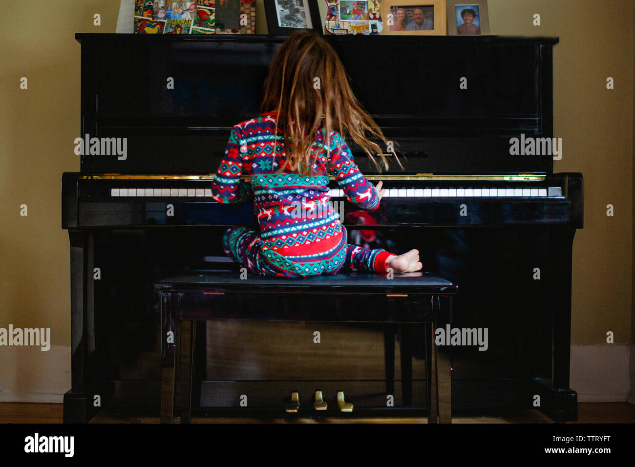 Una piccola ragazza a piedi nudi appassionatamente suona il pianoforte Foto Stock