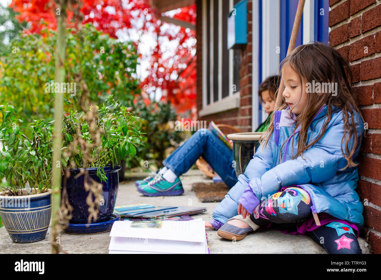 Due bambini seduti fuori su un fronte stoop la lettura di libri Foto Stock