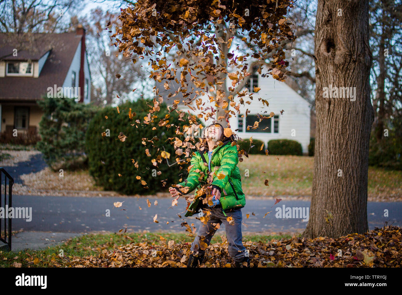 Un ragazzo gioioso getta foglie nel cielo Foto Stock