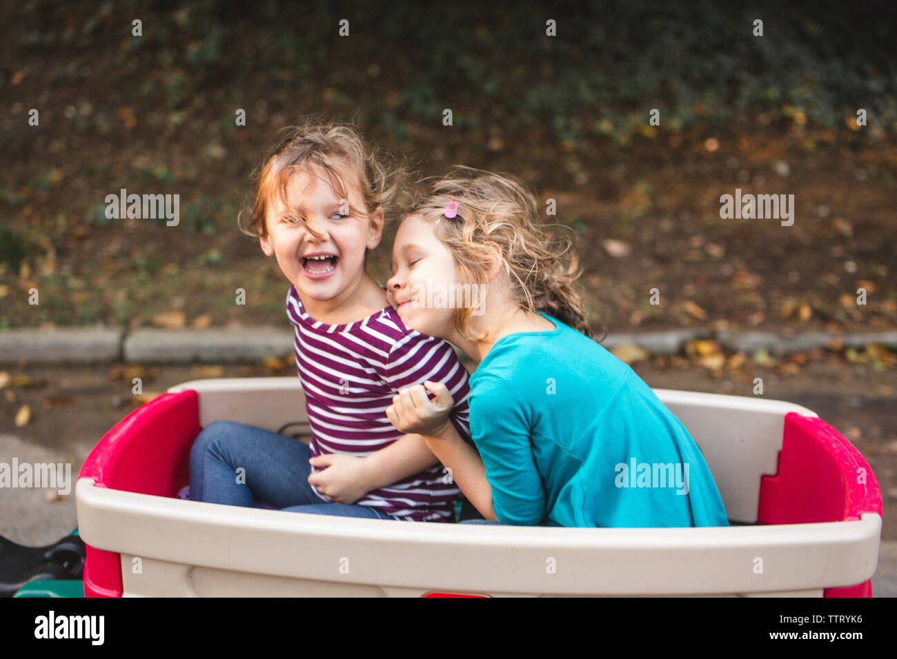 Felice di due bambine abbraccio in un carro su una bella passeggiata in famiglia Foto Stock