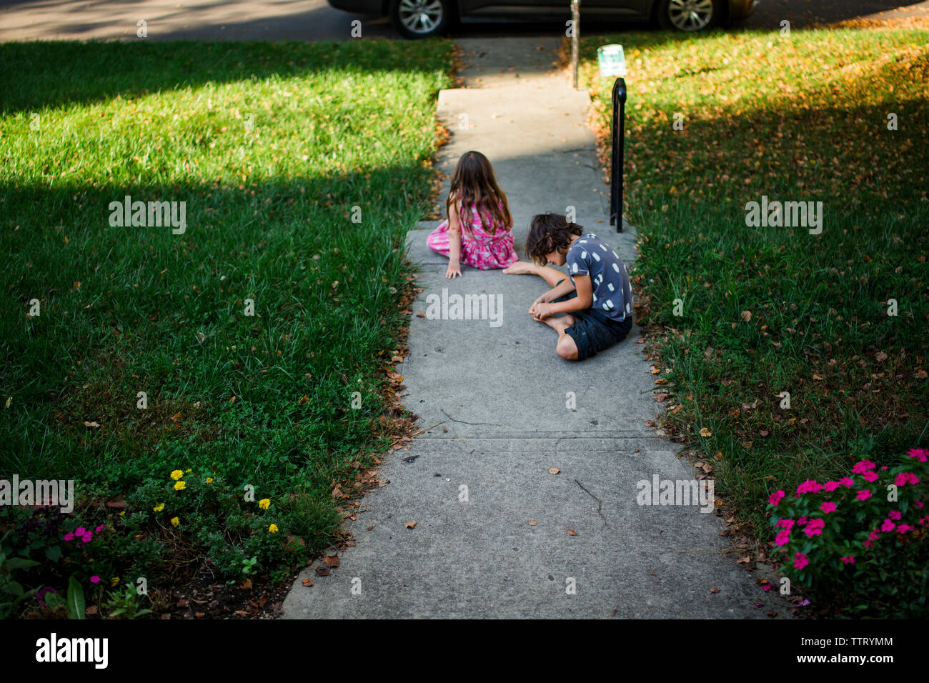 Un fratello e una sorella sedersi a piedi nudi nel loro cantiere in estate Foto Stock