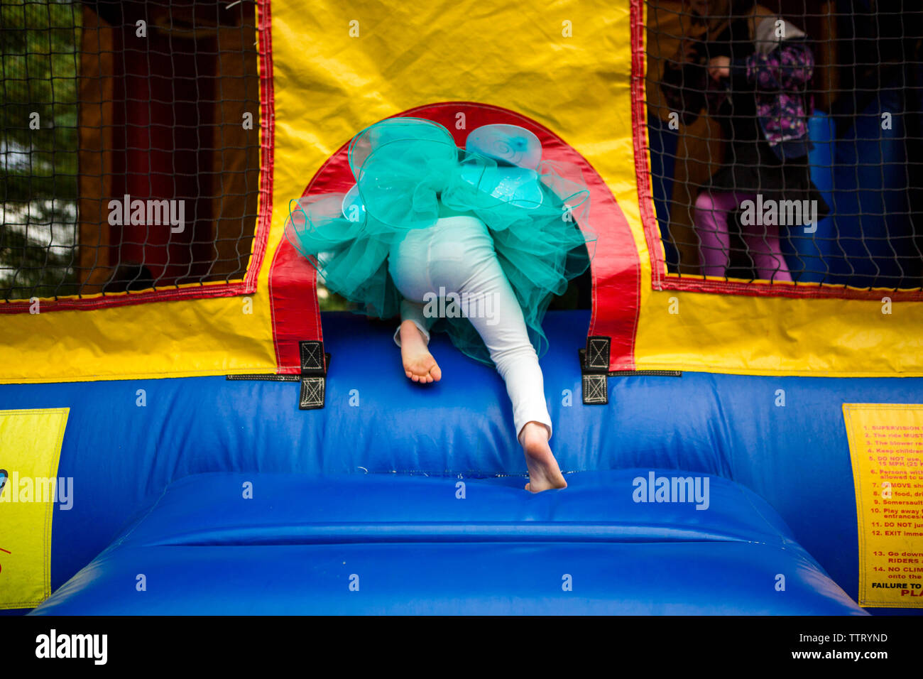 La metà inferiore di un bambino in un tutu arrampicata in un bouncehouse Foto Stock