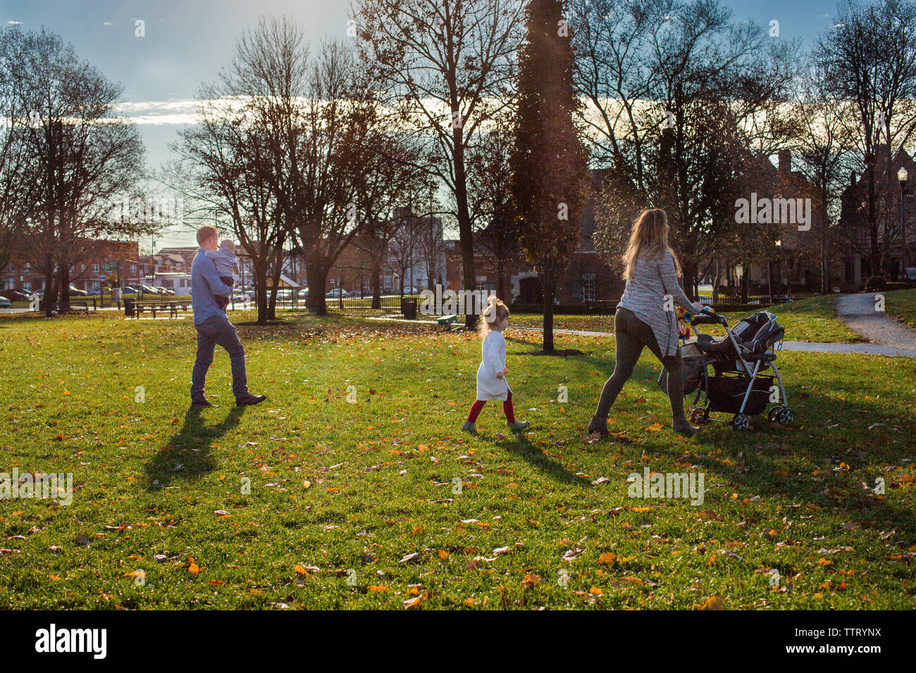 Una famiglia di camminare insieme in un soleggiato parco in autunno Foto Stock