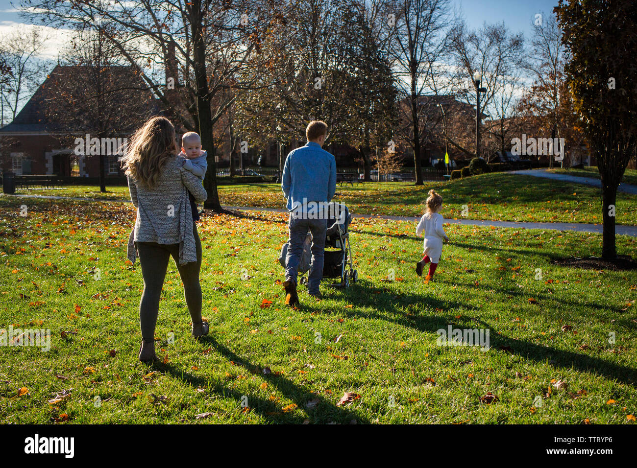 Una famiglia prendere un camminare insieme in un parco su una soleggiata giornata di caduta Foto Stock