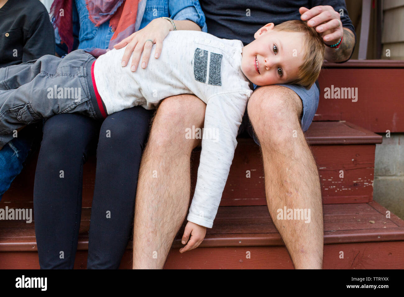 Un bambino piccolo poggia su i suoi genitori al di fuori giri Foto Stock