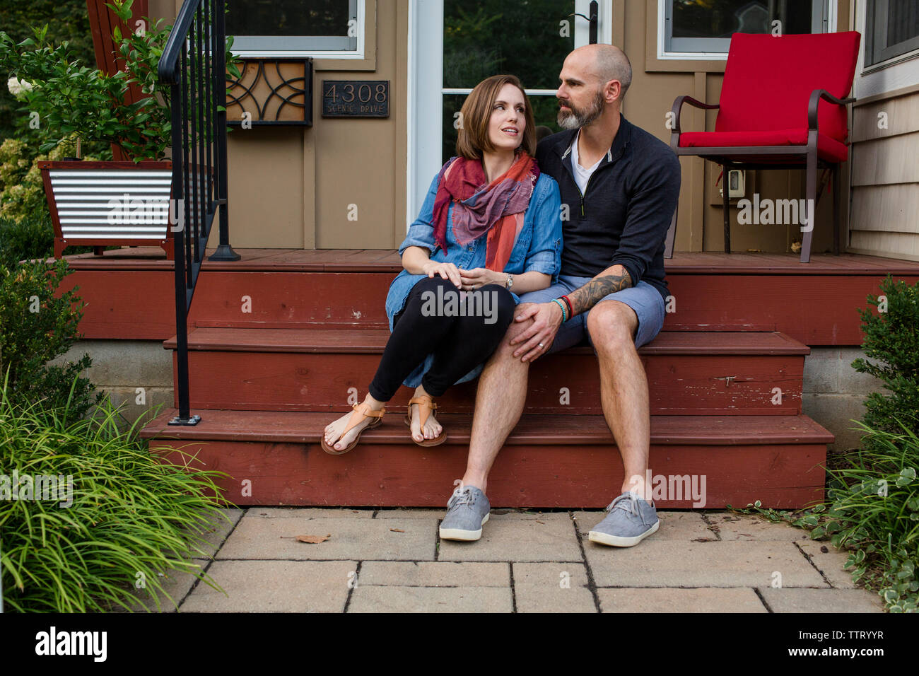 Una felice moglie si siede vicino al marito sulla parte anteriore stoop Foto Stock