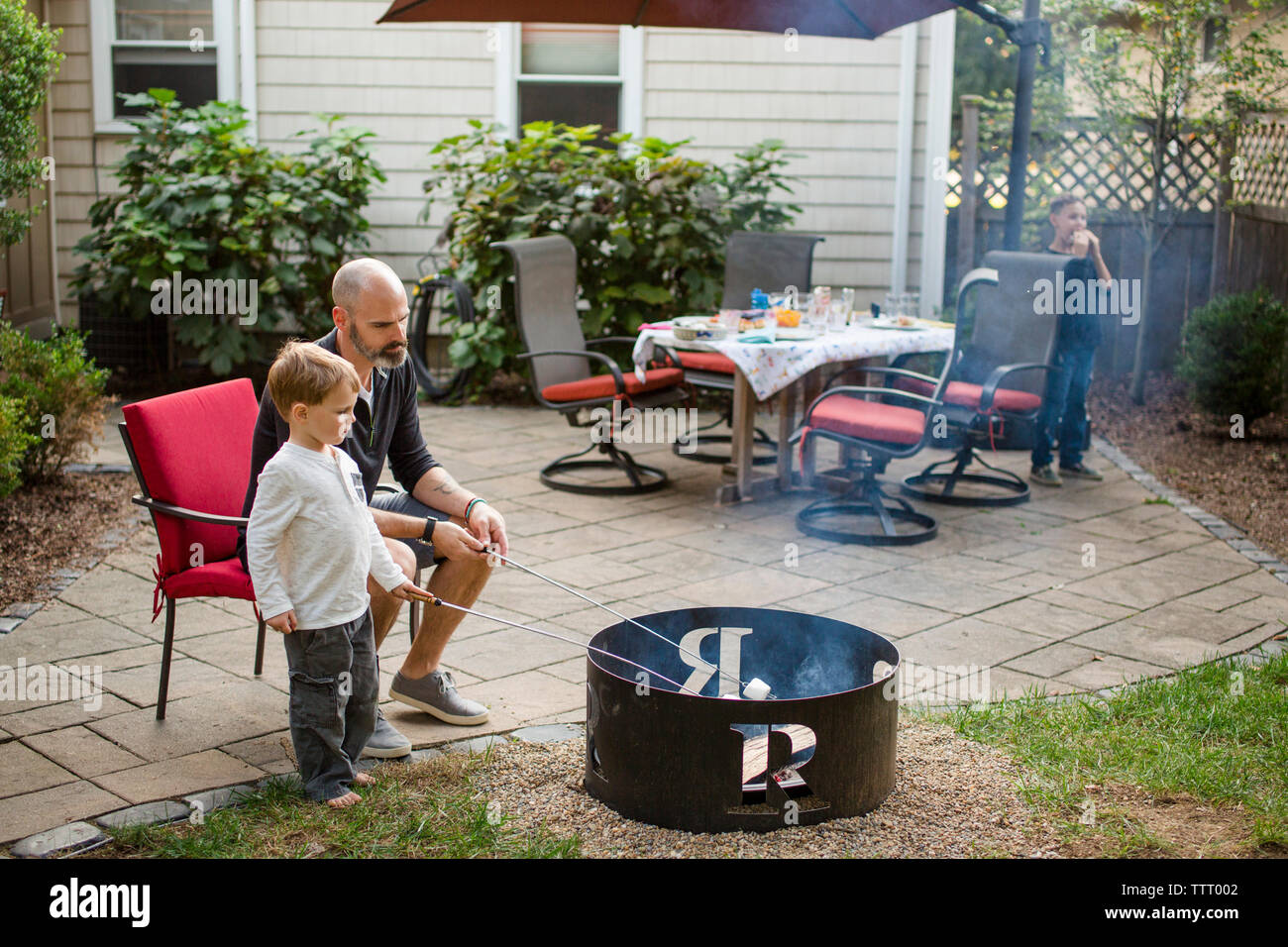 Un padre arrosti marshmallows con bambini in cortile Foto Stock