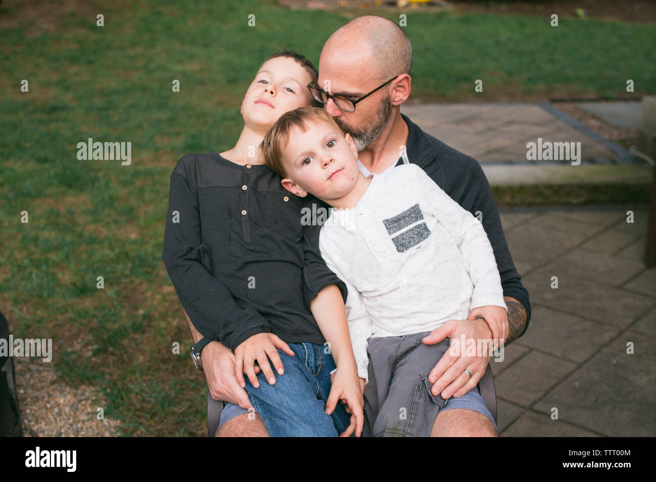 Un felice padre abbraccia i suoi due bambini piccoli Foto Stock