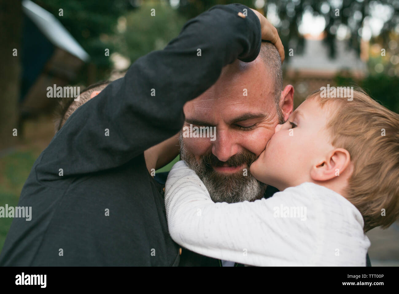 Un padre Felice è baciato dai suoi due bambini piccoli Foto Stock
