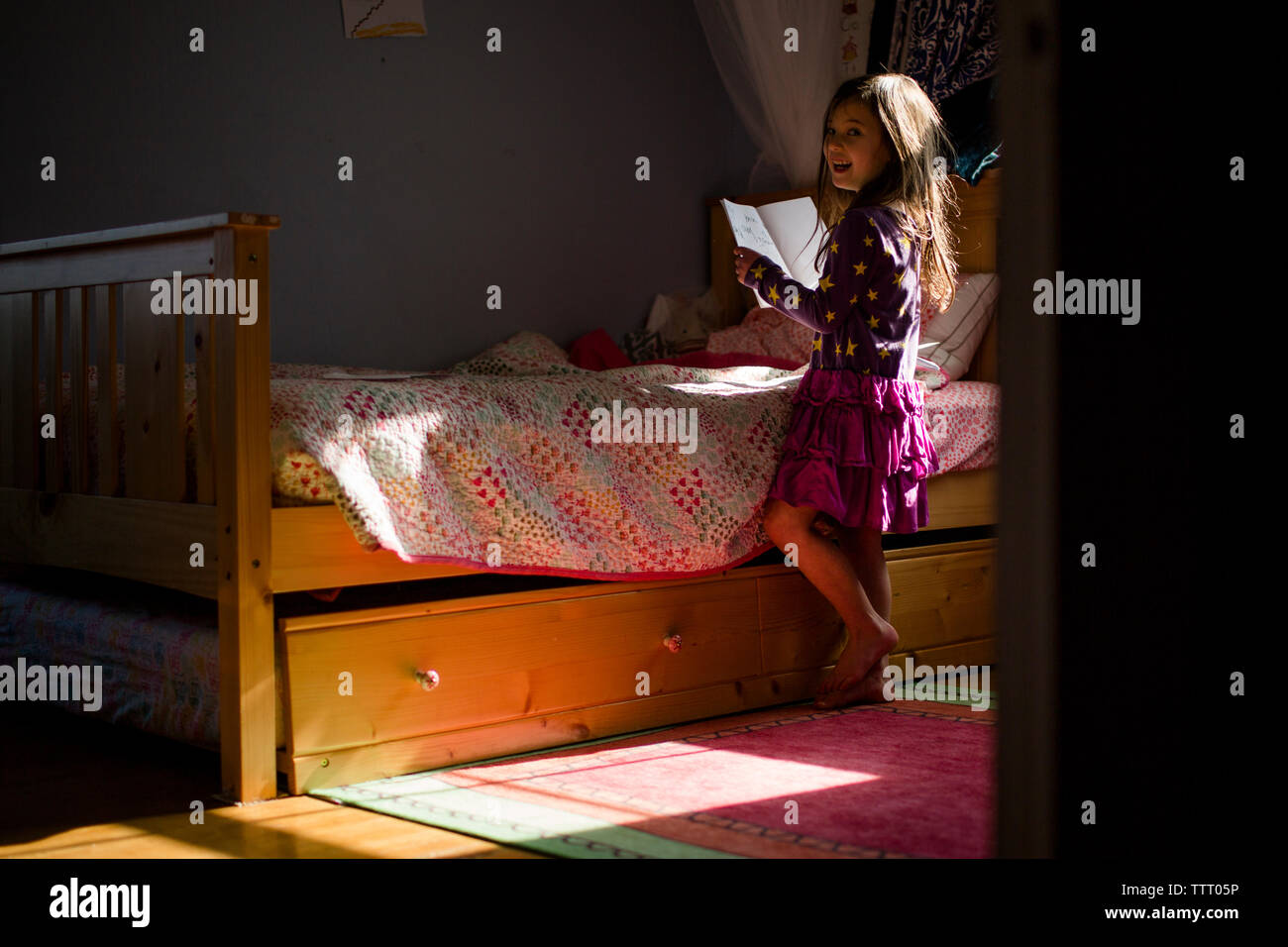 Ritratto di un felice bambina la lettura di un libro da sola nella sua camera da letto Foto Stock
