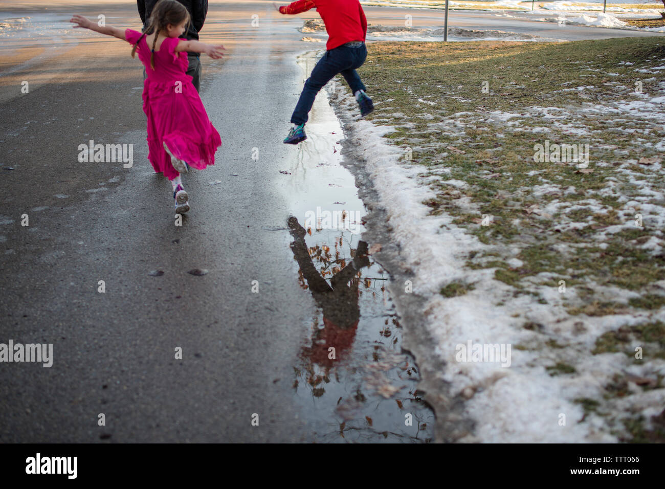 Due bambini felici leap e danza sulla passeggiata lungo la strada con il padre Foto Stock