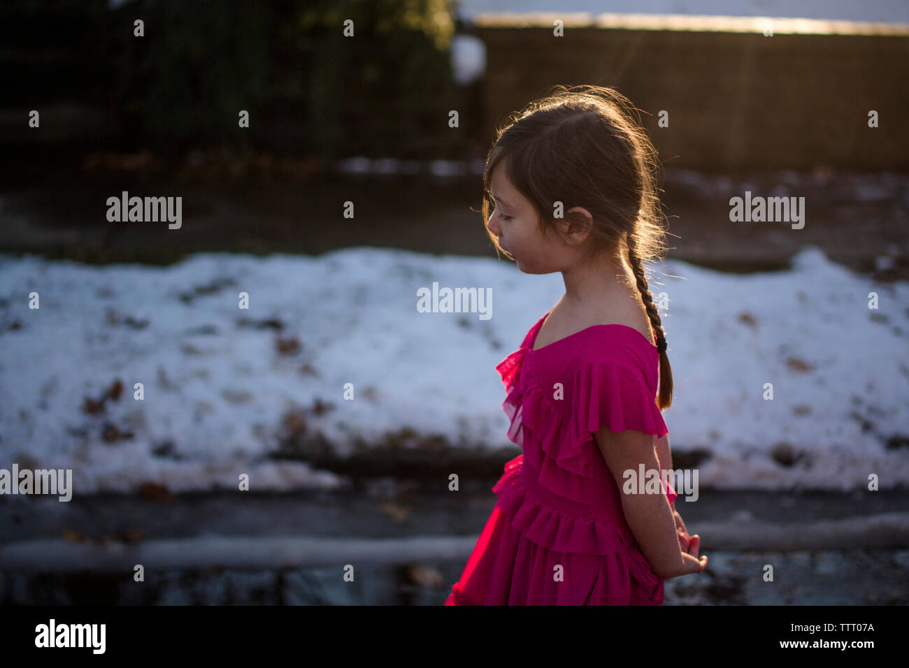 Una piccola ragazza con lunghe trecce e fancy dress a camminare nella luce dorata Foto Stock