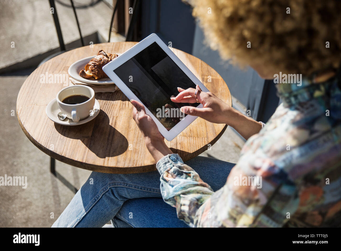 Elevato angolo di visione della donna con tavoletta digitale mentre seduti al cafè sul marciapiede Foto Stock