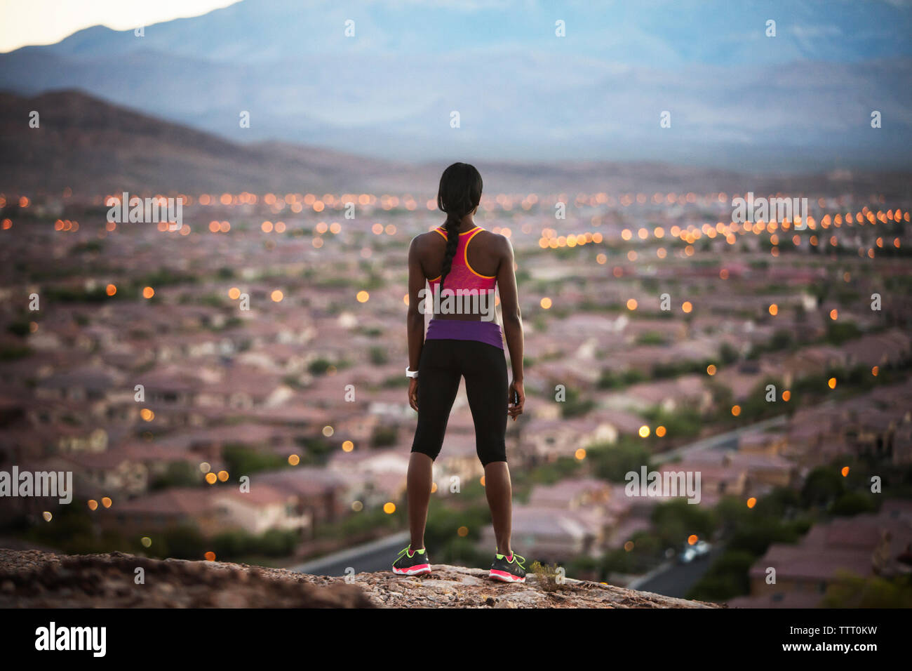 Vista posteriore della donna in piedi sulla collina mentre guarda il paesaggio illuminato Foto Stock