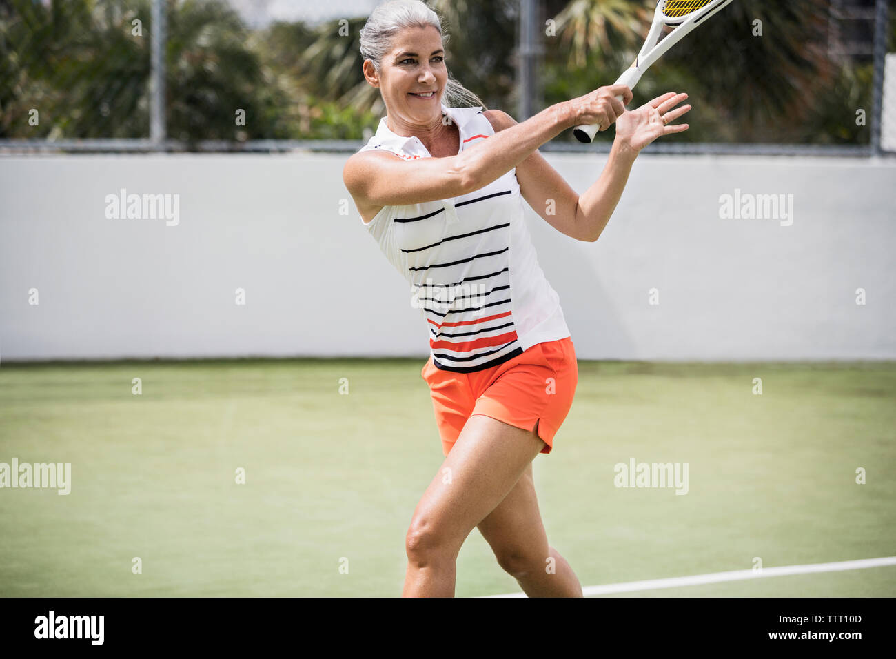 Donna matura giocando a tennis a corte Foto Stock