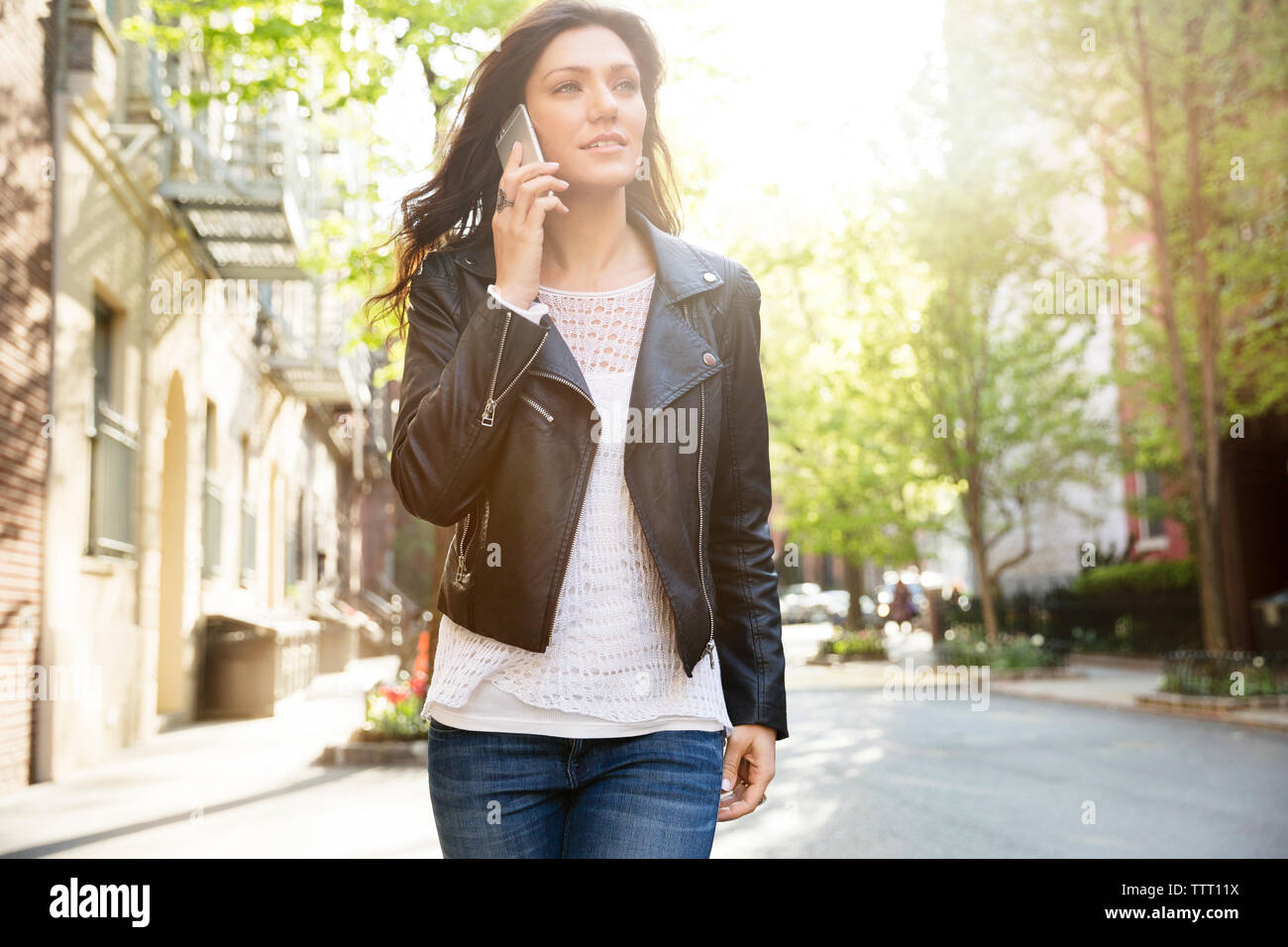 Bella donna rispondendo alle smart phone mentre si cammina sulla strada Foto Stock