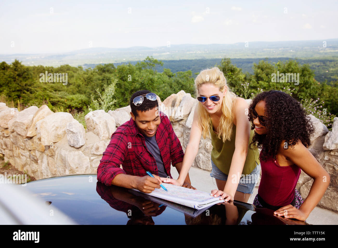 Amici di viaggio di pianificazione sulla mappa durante la vacanza con il paesaggio sullo sfondo Foto Stock