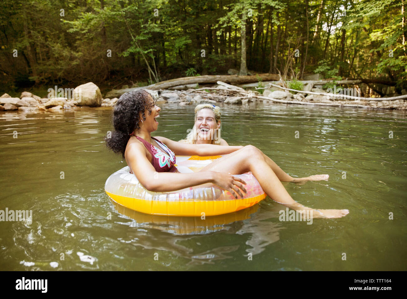 Allegro amiche ridere utilizzando tubi interni in fiume Foto Stock