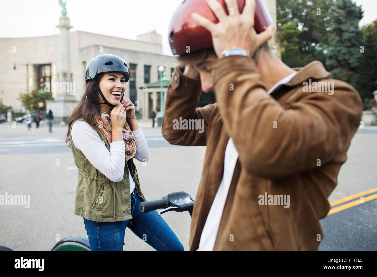 Giovane che indossa caschi in bicicletta mentre in piedi su una strada di città Foto Stock