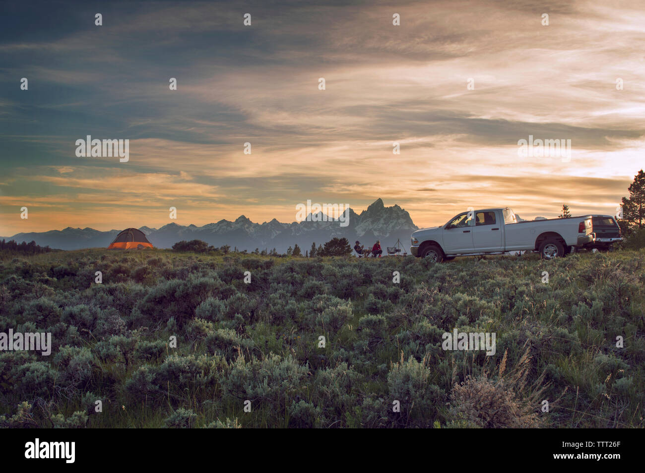 Vista in lontananza gli amici seduti sul campo contro sky Foto Stock