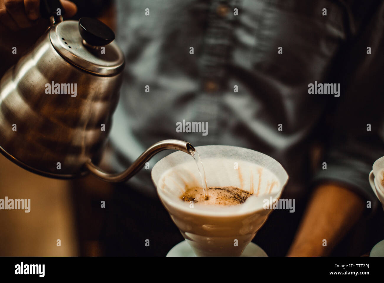 Sezione mediana del barista versando acqua nel filtro di caffè al caffè Foto Stock