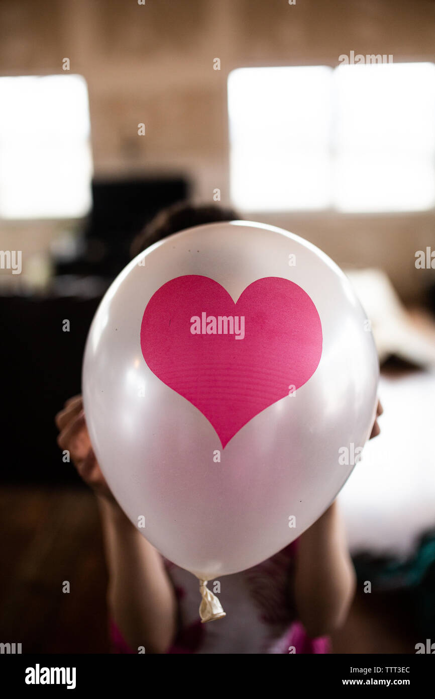 Ragazza con palloncino cuore davanti la sua testa Foto Stock