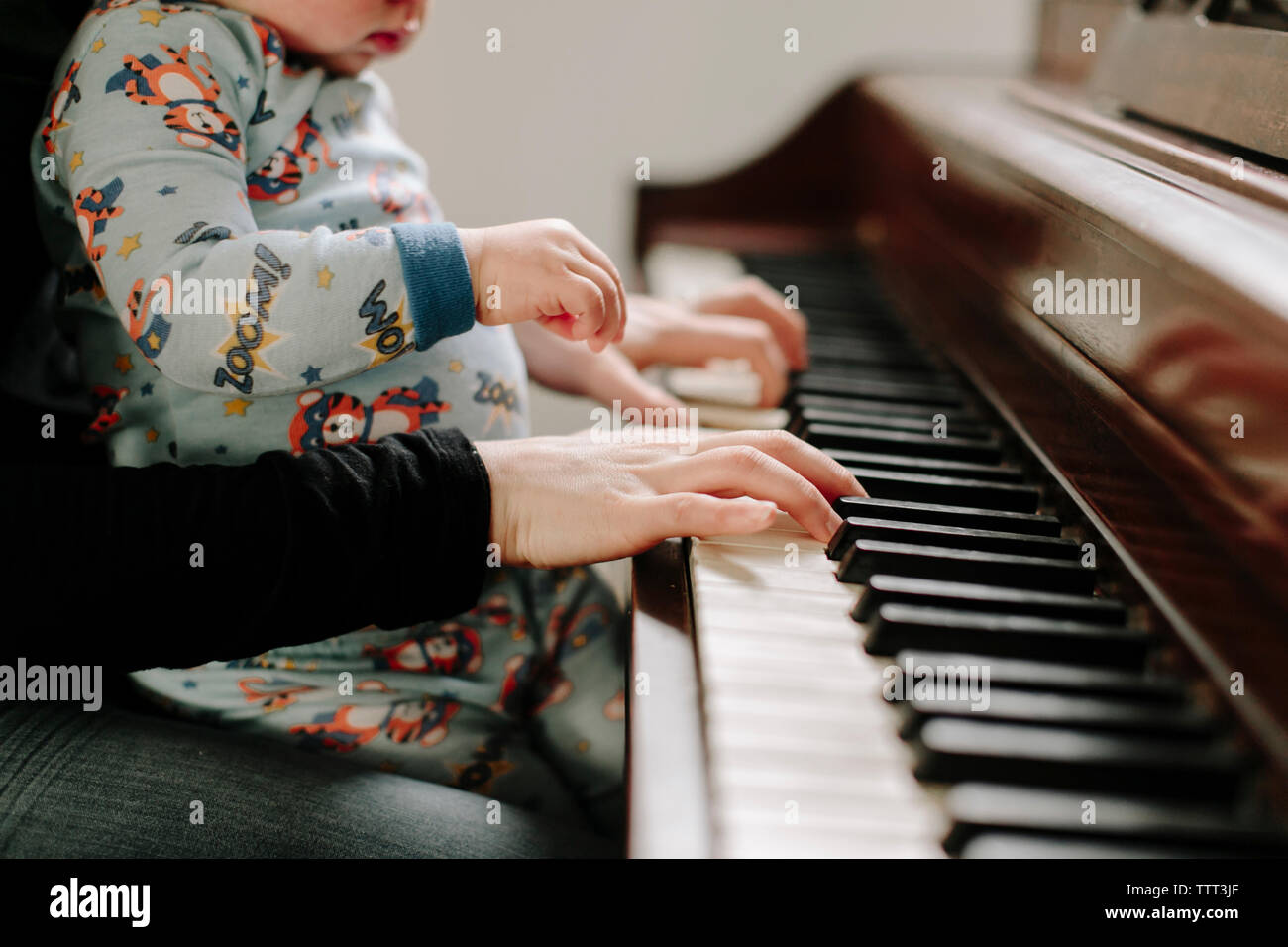 Sezione mediana della madre con figlio suonare il pianoforte a casa Foto Stock