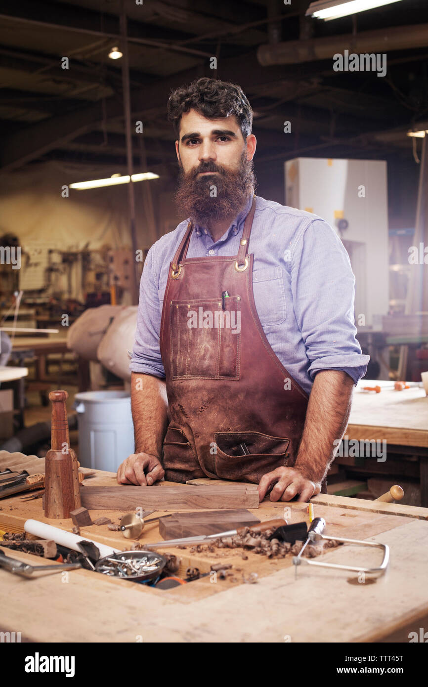 Ritratto di fiducioso artigiano permanente al negozio di legno Foto Stock