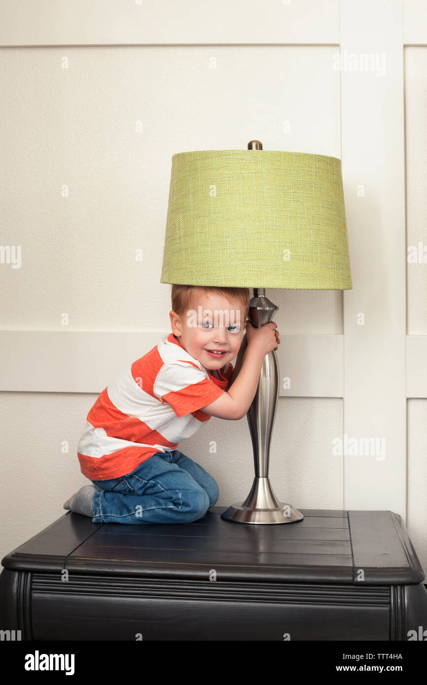 Ritratto di ragazzo holding e giocare con la lampada sul tavolo Foto Stock