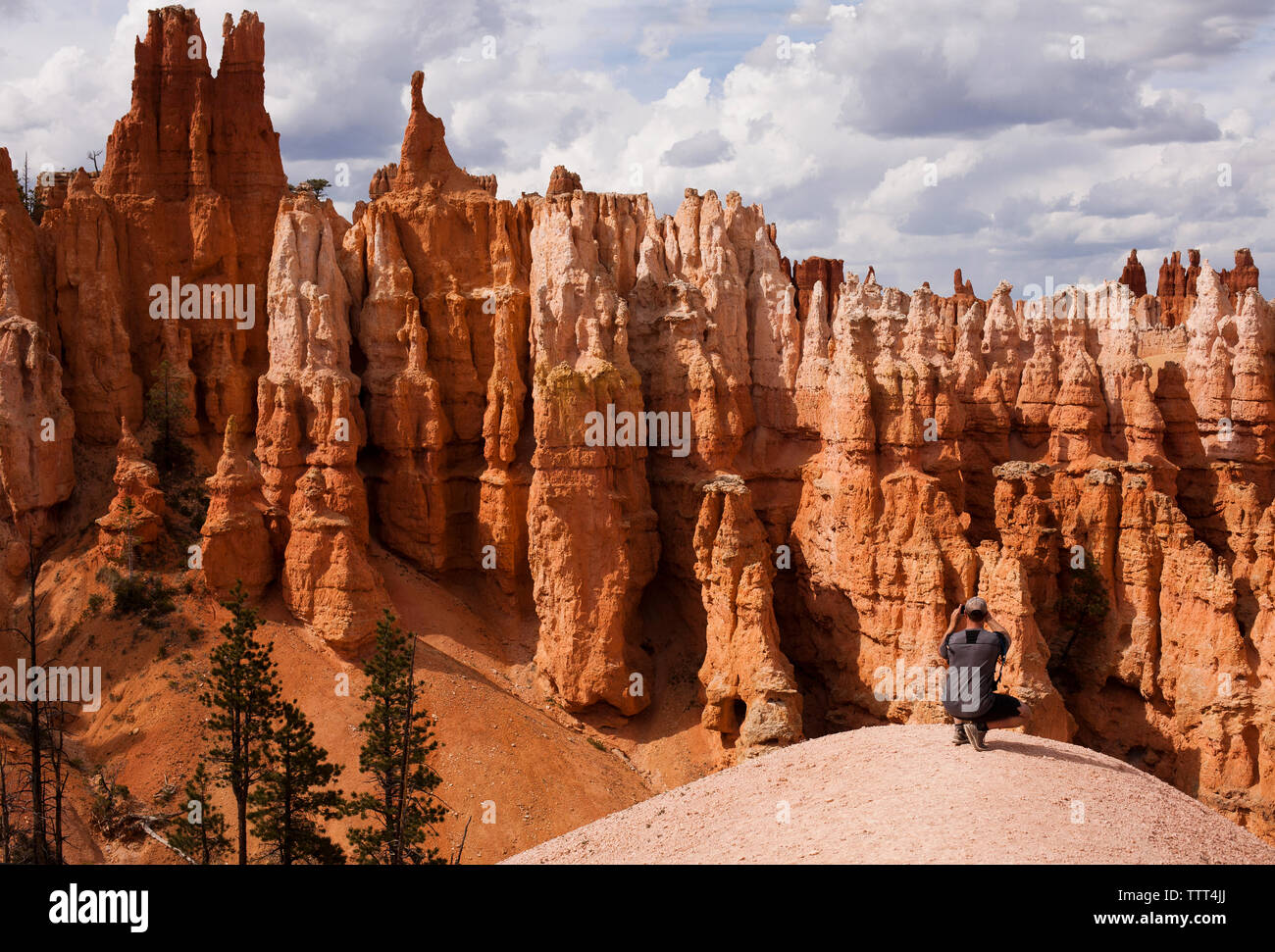 Uomo hoodoos fotografare mentre accovacciato su roccia Foto Stock