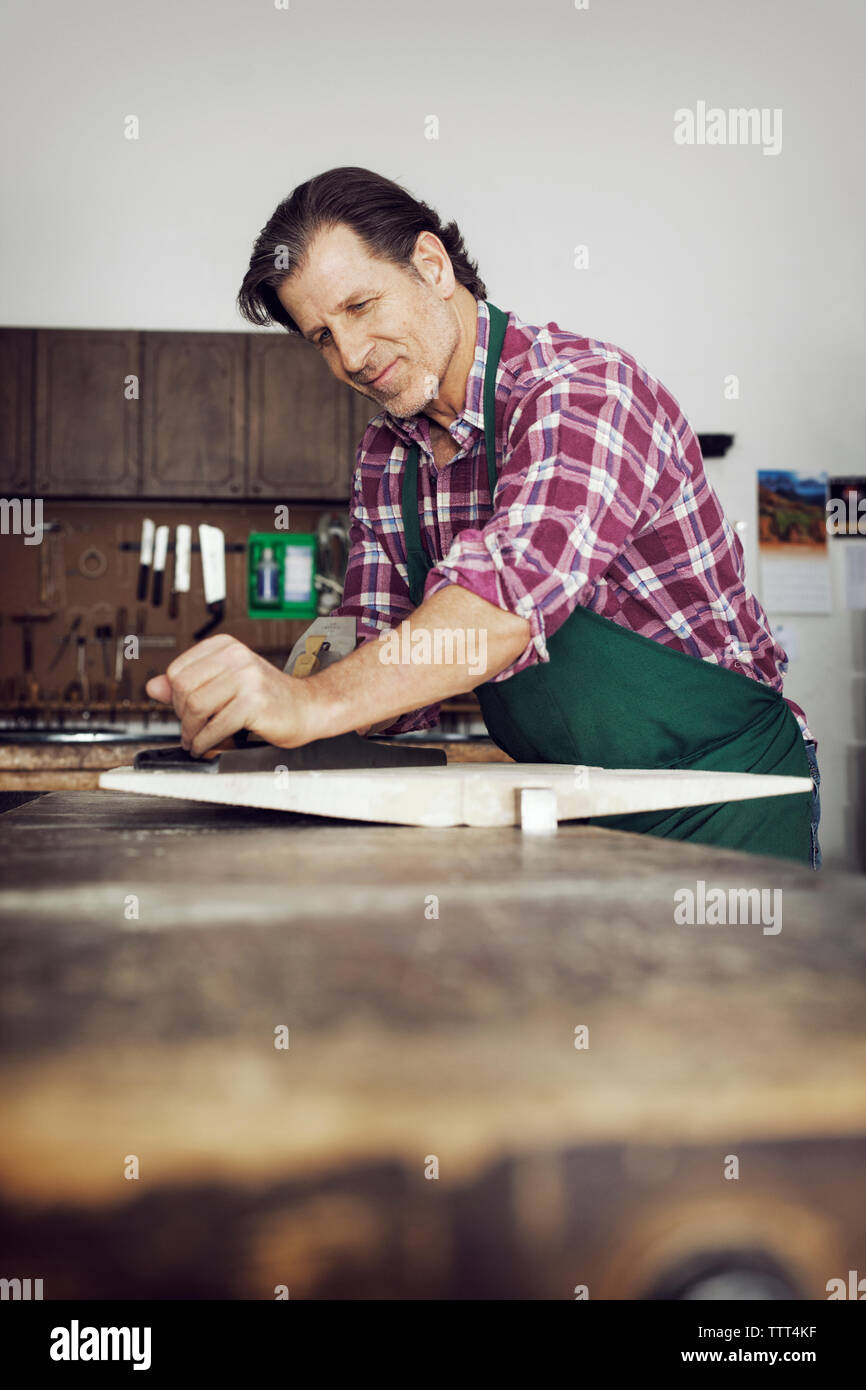 Uomo sorridente segatura di legno in officina Foto Stock