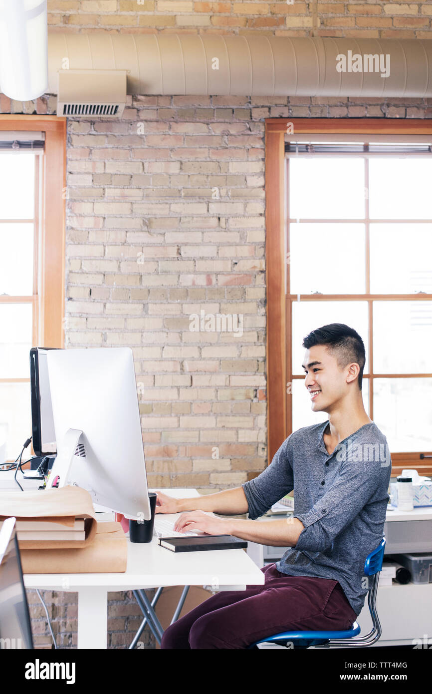uomo d'affari che utilizza un computer desktop mentre lavora in ufficio Foto Stock