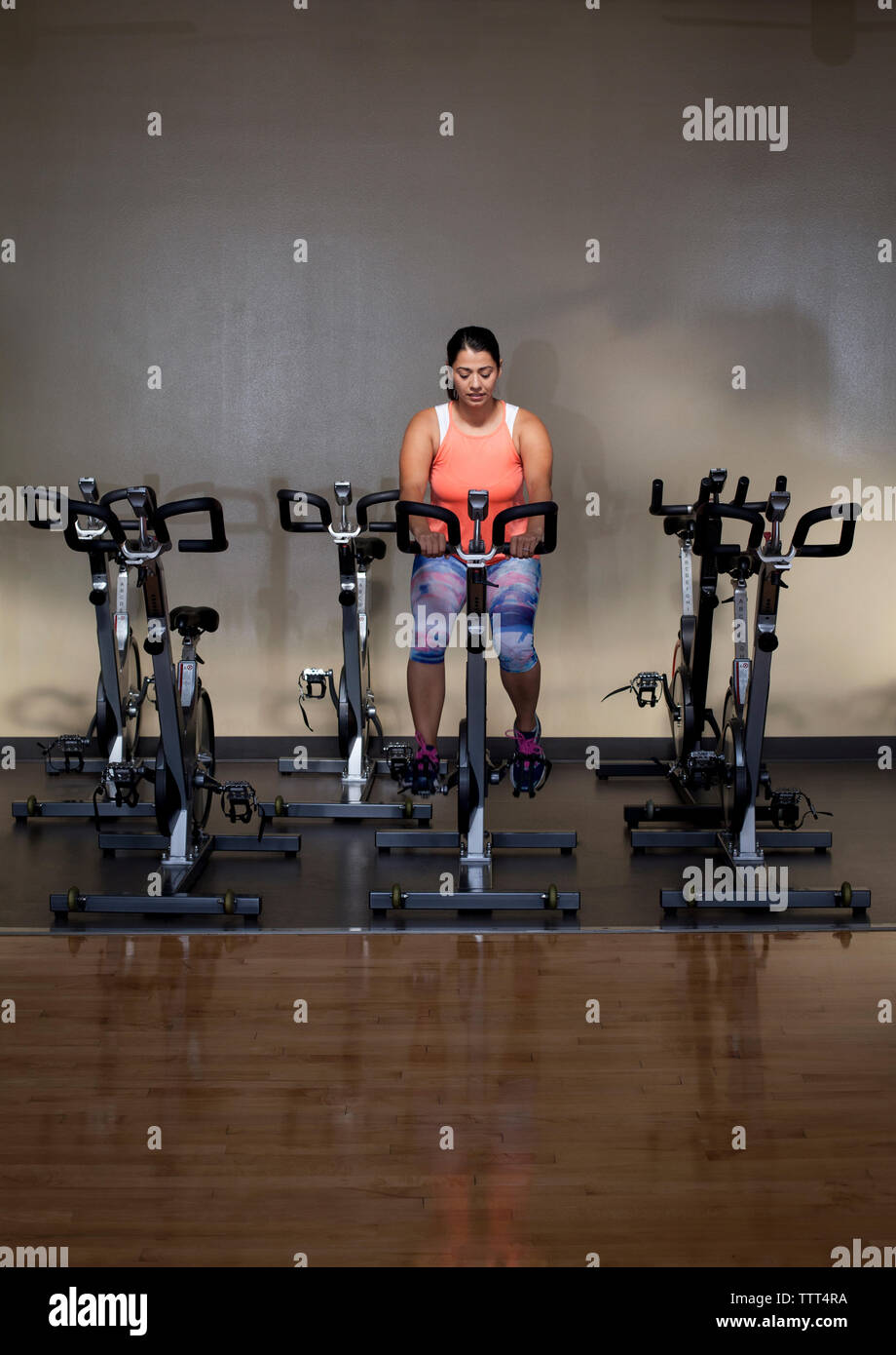 Per tutta la lunghezza della donna che esercitano sulla cyclette in palestra Foto Stock