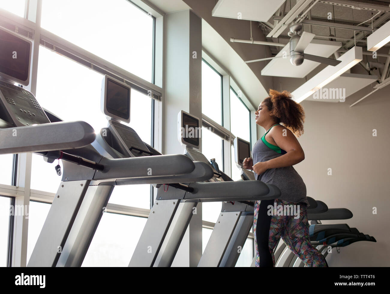 Vista laterale della curva donna in corsa sul tapis roulant in palestra Foto Stock
