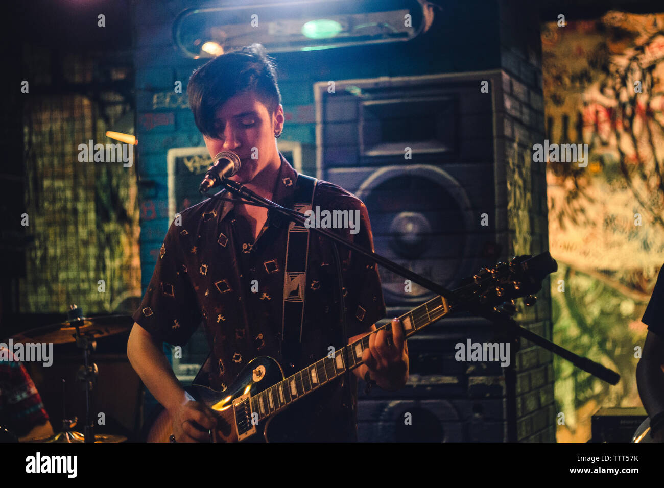 Fiducioso uomo di cantare e suonare la chitarra in discoteca Foto Stock