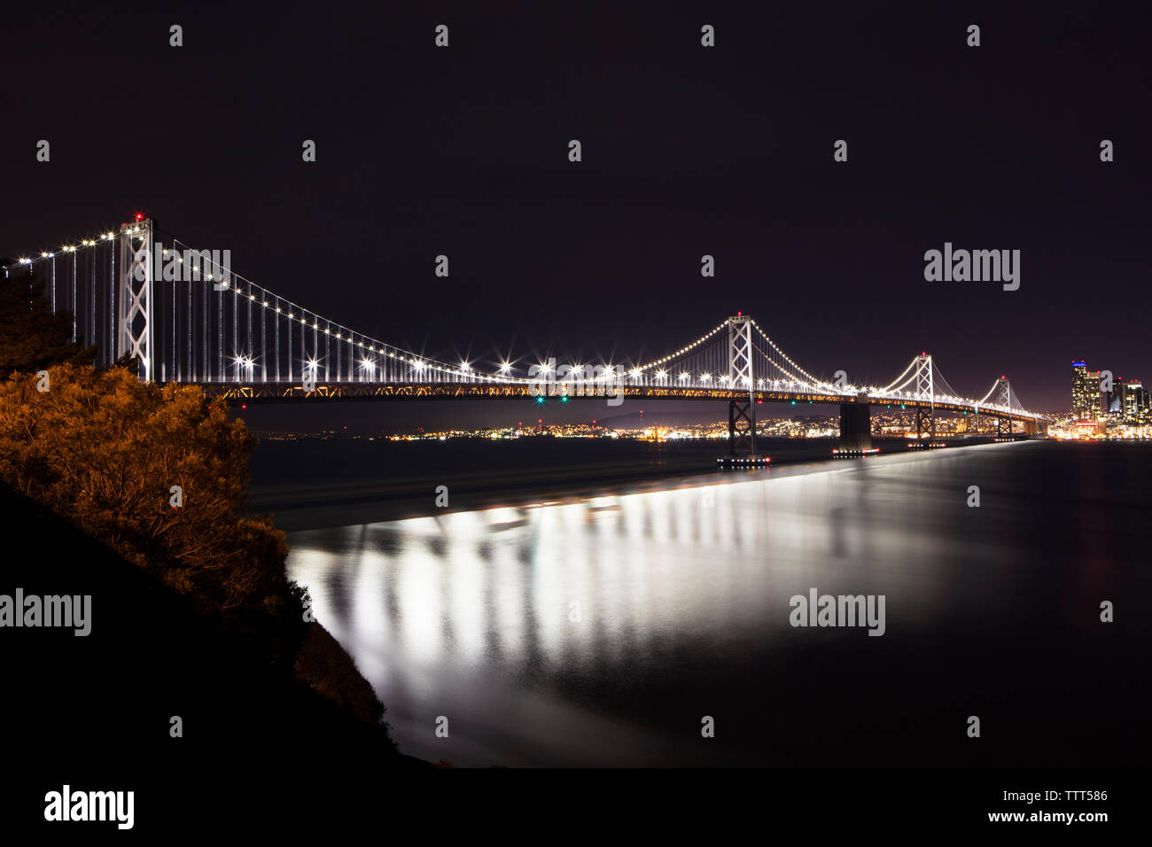 Illuminata Oakland Bay Bridge su mare contro il cielo di notte Foto Stock