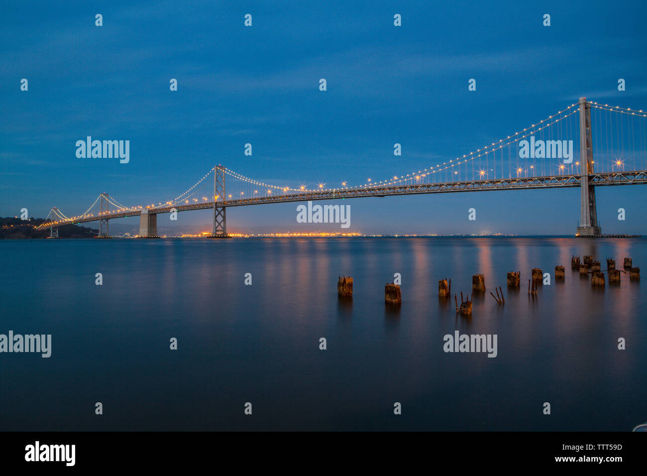 Illuminata Oakland Bay Bridge contro il cielo blu al tramonto Foto Stock