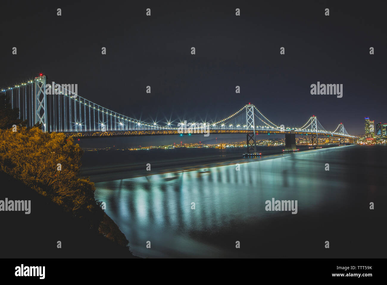 Illuminata Oakland Bay Bridge contro il cielo chiaro di notte Foto Stock