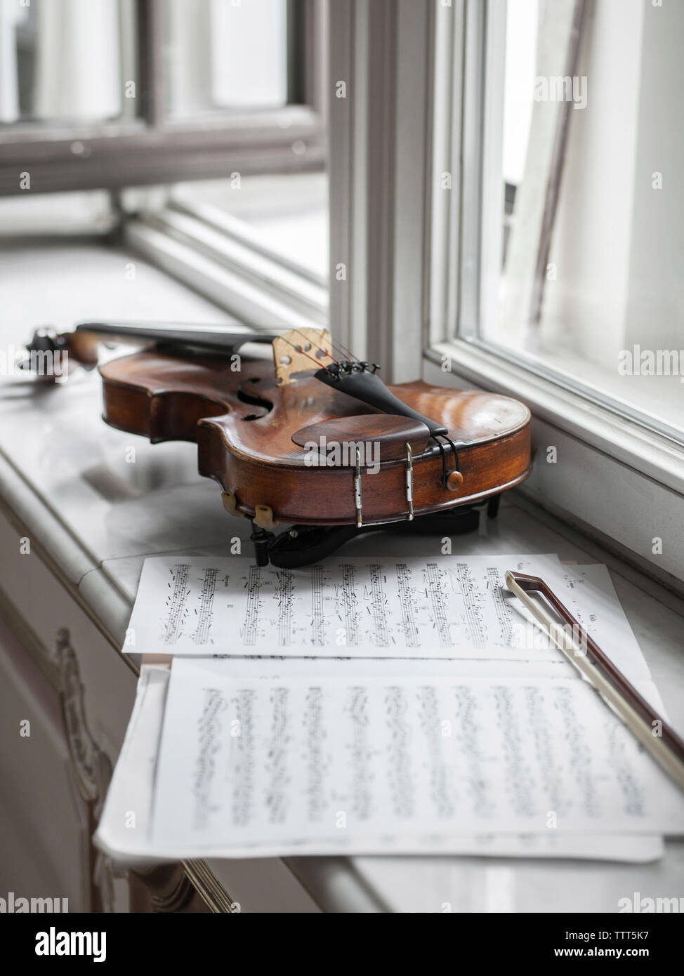 Angolo di Alta Vista del violino con foglio di musica e la prua sul davanzale nella mansion Foto Stock
