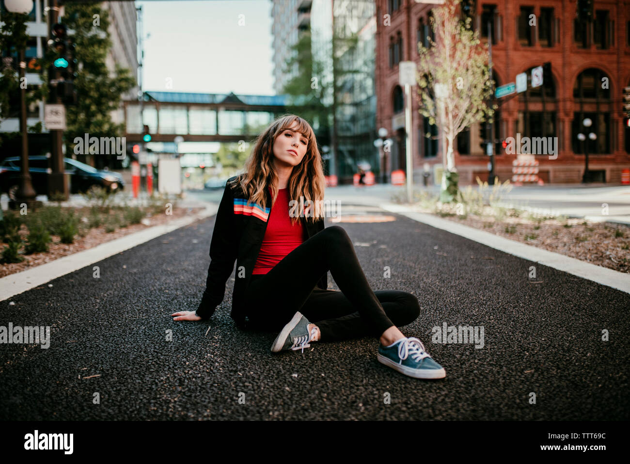 Ritratto di giovane donna seduta su una strada di città Foto Stock