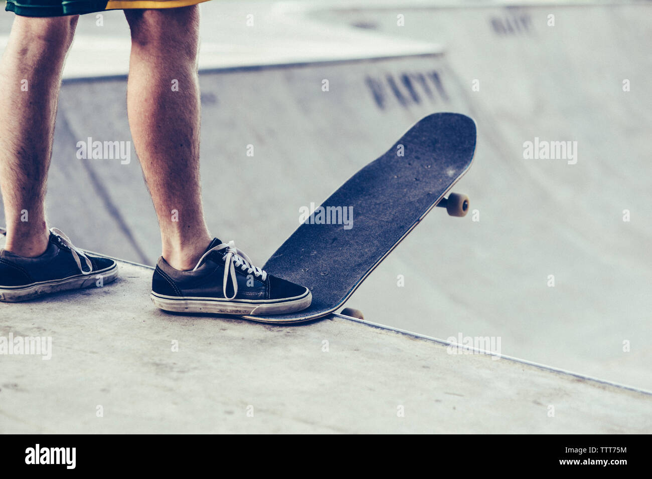 Sezione bassa del giovane con lo skateboard in corrispondenza del bordo della rampa di sport Foto Stock