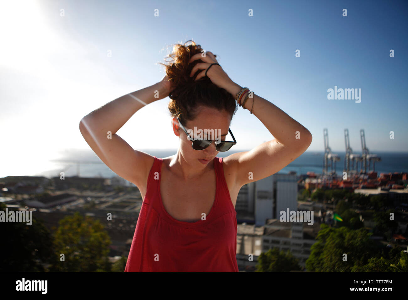 Donna con le mani nei capelli in piedi contro il cielo Foto Stock
