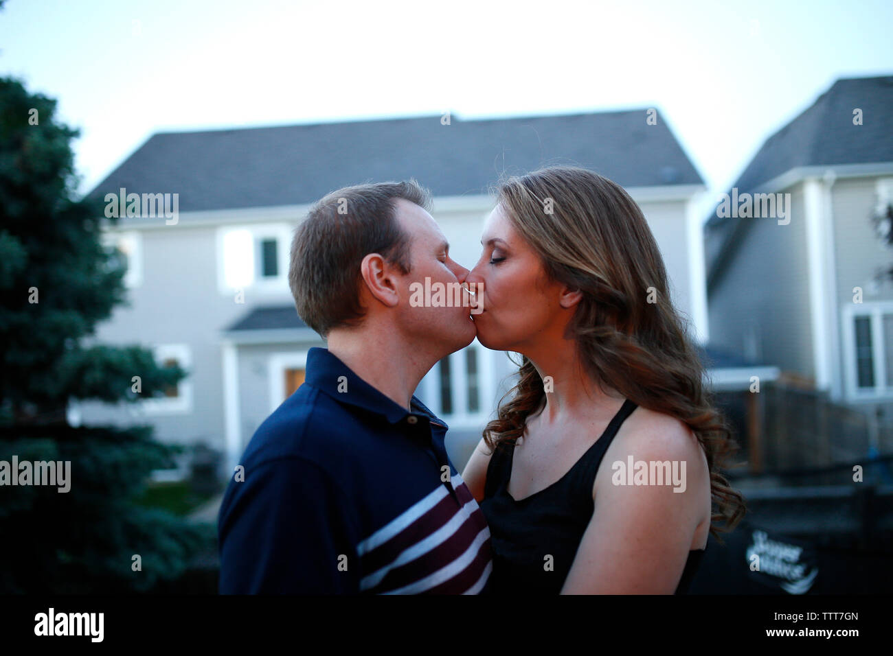 Coppia romantica baciare permanente, mentre in patio contro house Foto Stock