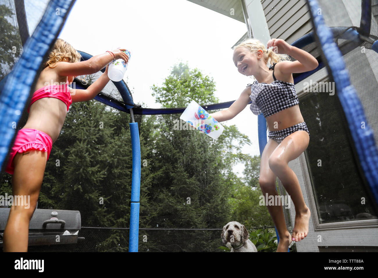 Sorelle di ridere avente acqua lotta sul trampolino in estate Foto Stock