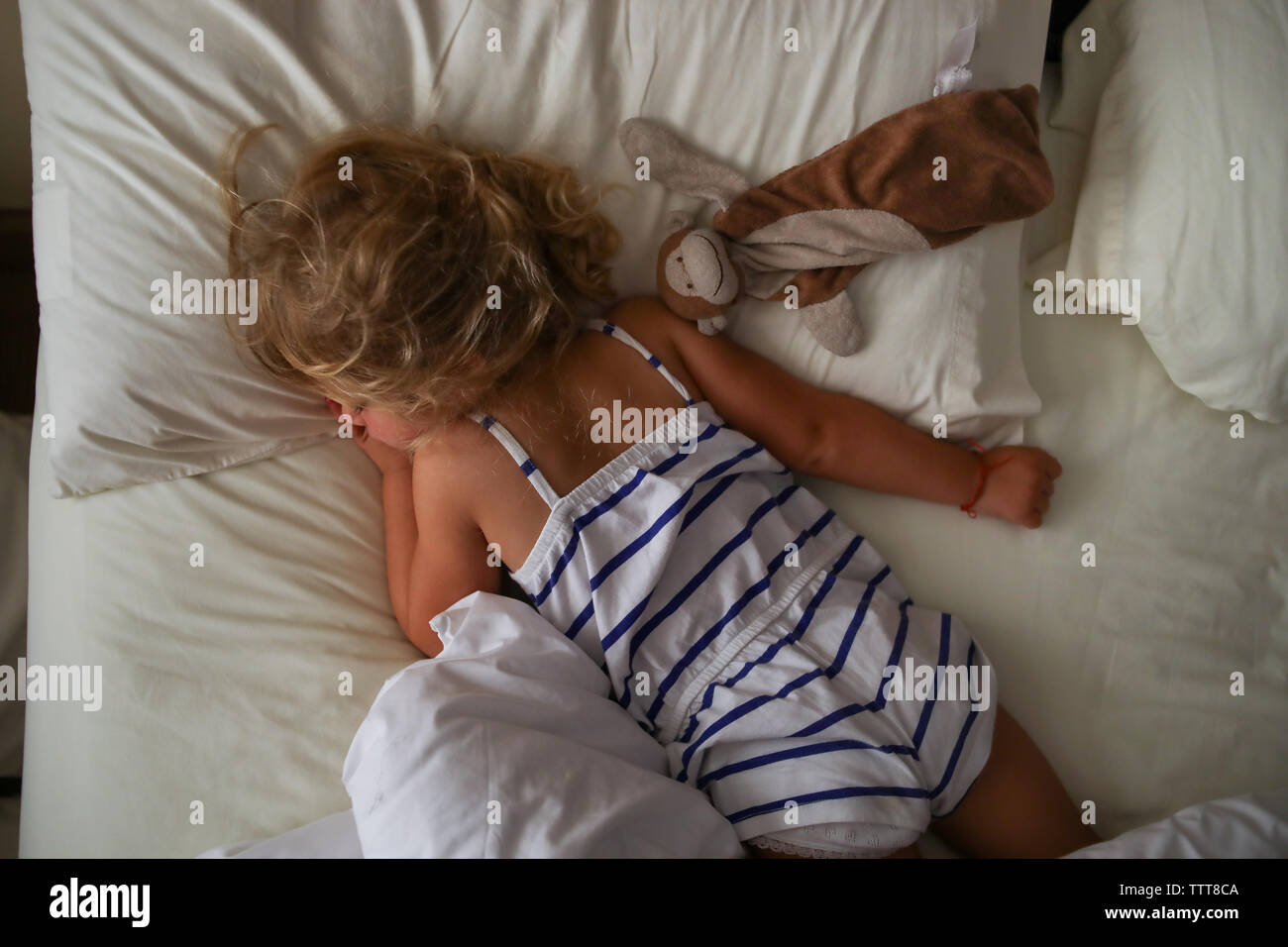 Vista aerea del bimbo che dorme con lovey a letto indossando striped pj Foto Stock