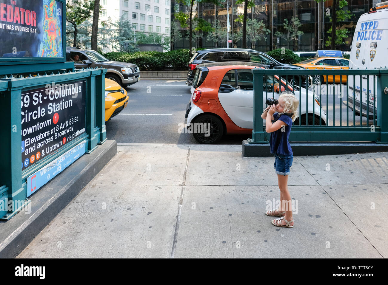 Giovane ragazza tenendo la foto con la fotocamera del segno nella città di new york sulla strada Foto Stock